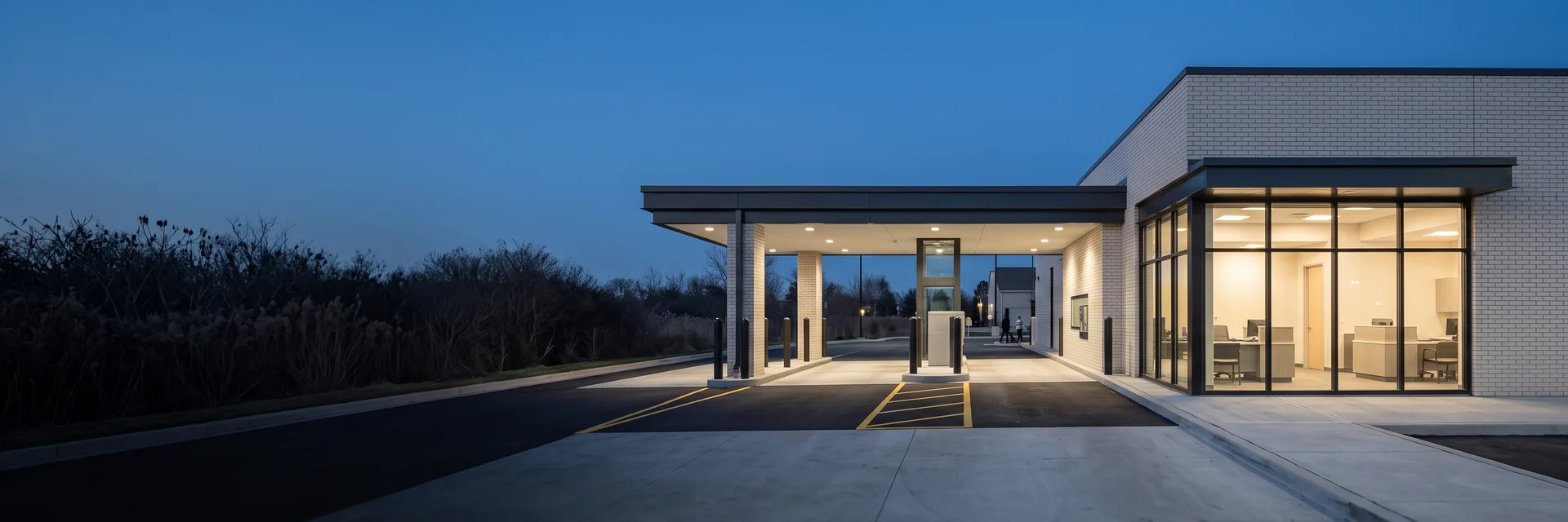 Modern bank branch exterior at dusk with a drive-up canopy and lit entry