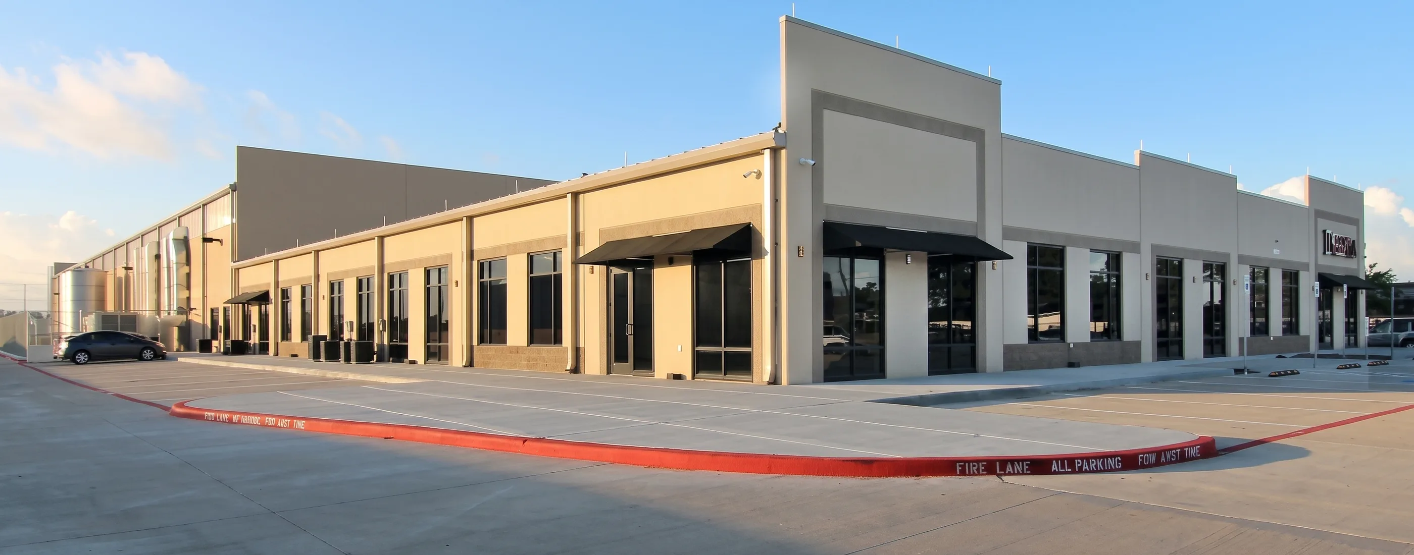 Dishaka office elevation with storefront glazing, awnings, and the tilt-wall facility running behind it