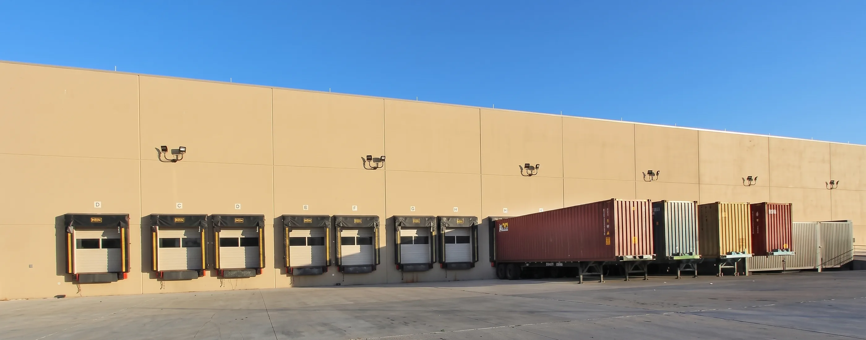 Row of dock doors on the Dishaka warehouse elevation with a trailer backed in
