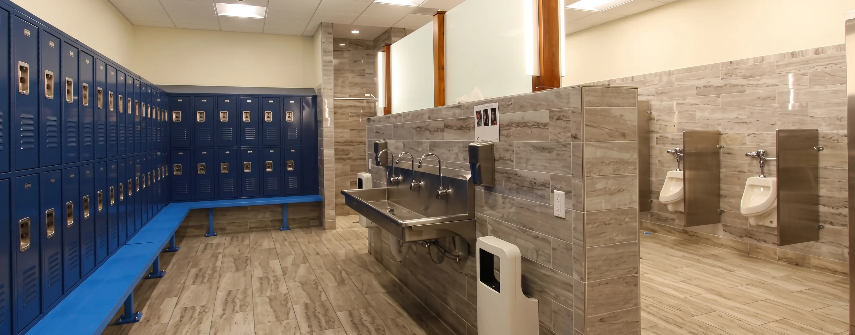 Employee locker room and restroom with tiled walls and a trough sink