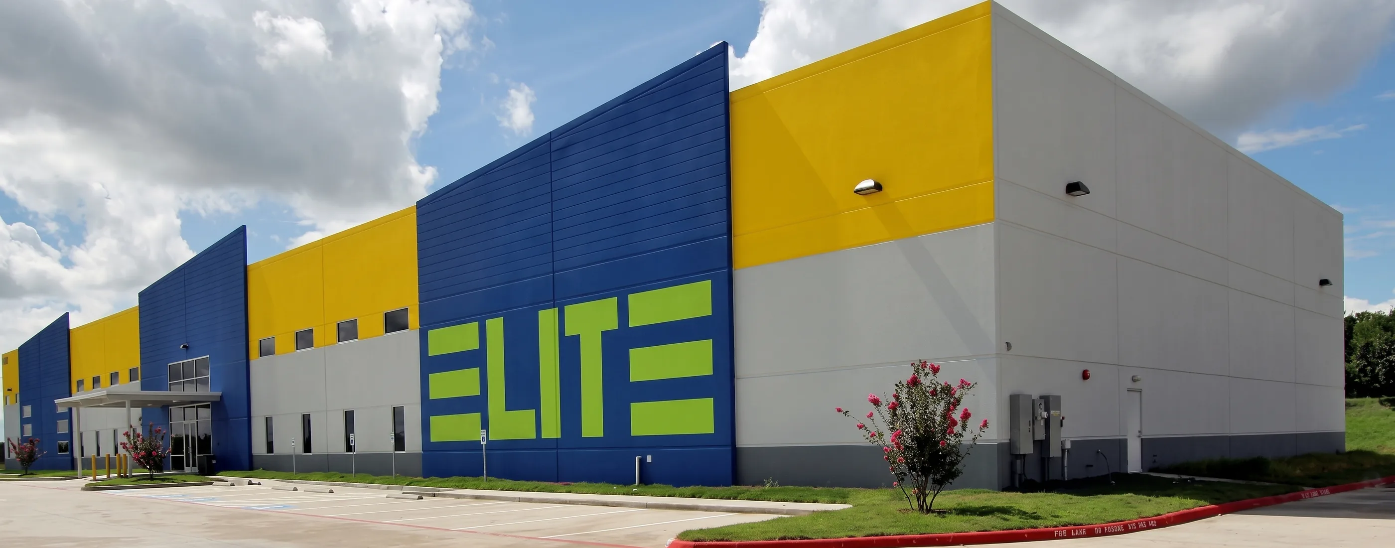 Elite Volleyball facility exterior with blue and yellow tilt-wall panels and the Elite sign