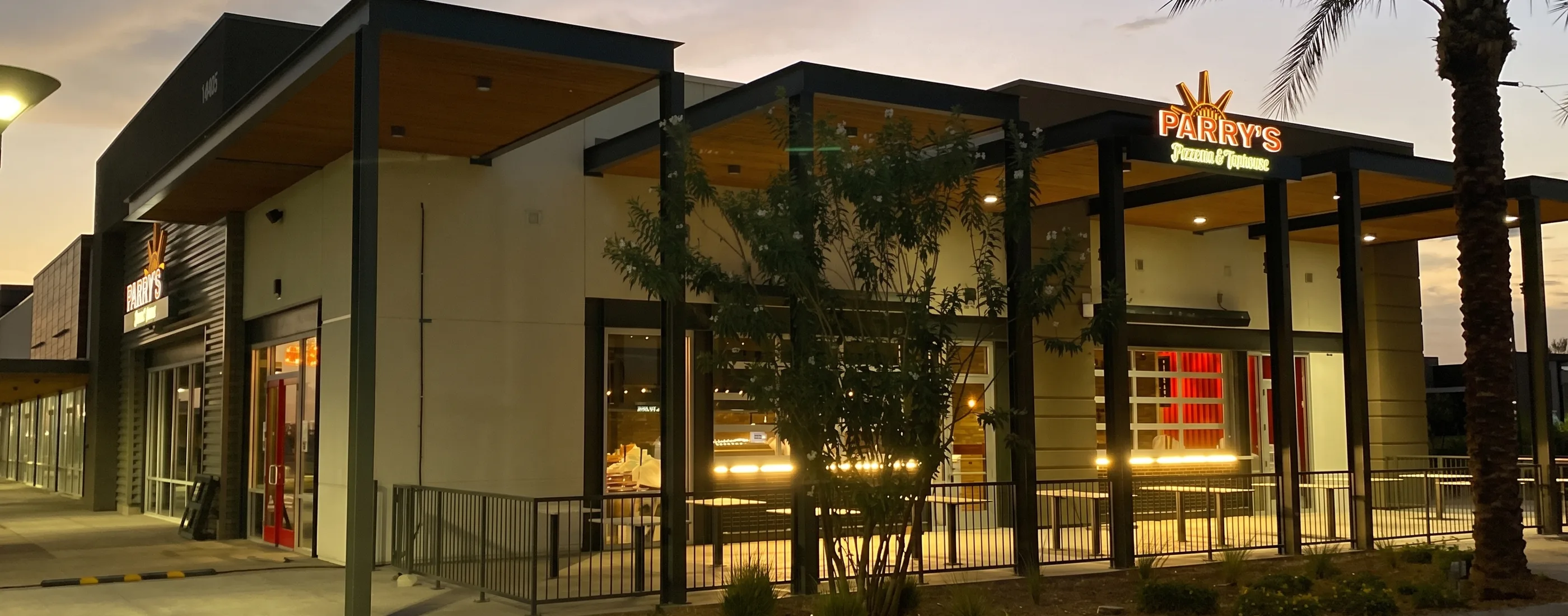 Parry’s Pizza entrance and patio at dusk with the restaurant sign lit