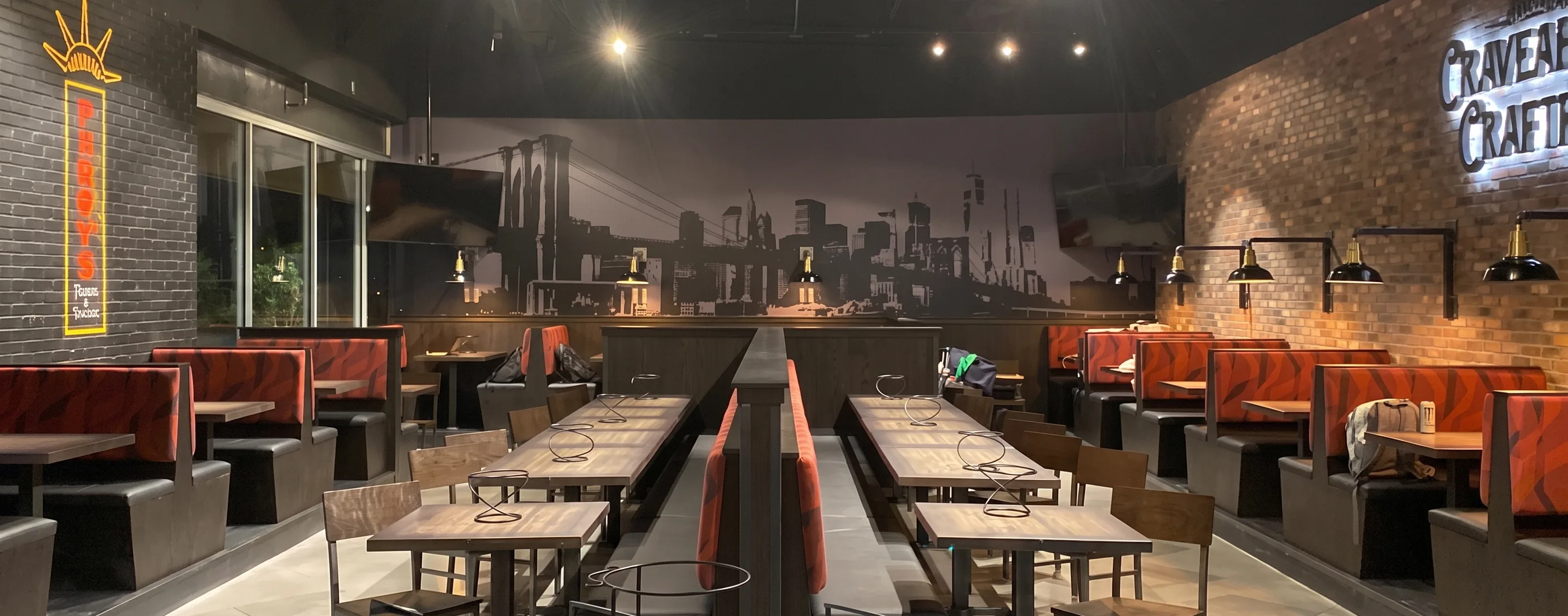 Parry’s Pizza dining room with communal tables and a New York skyline mural