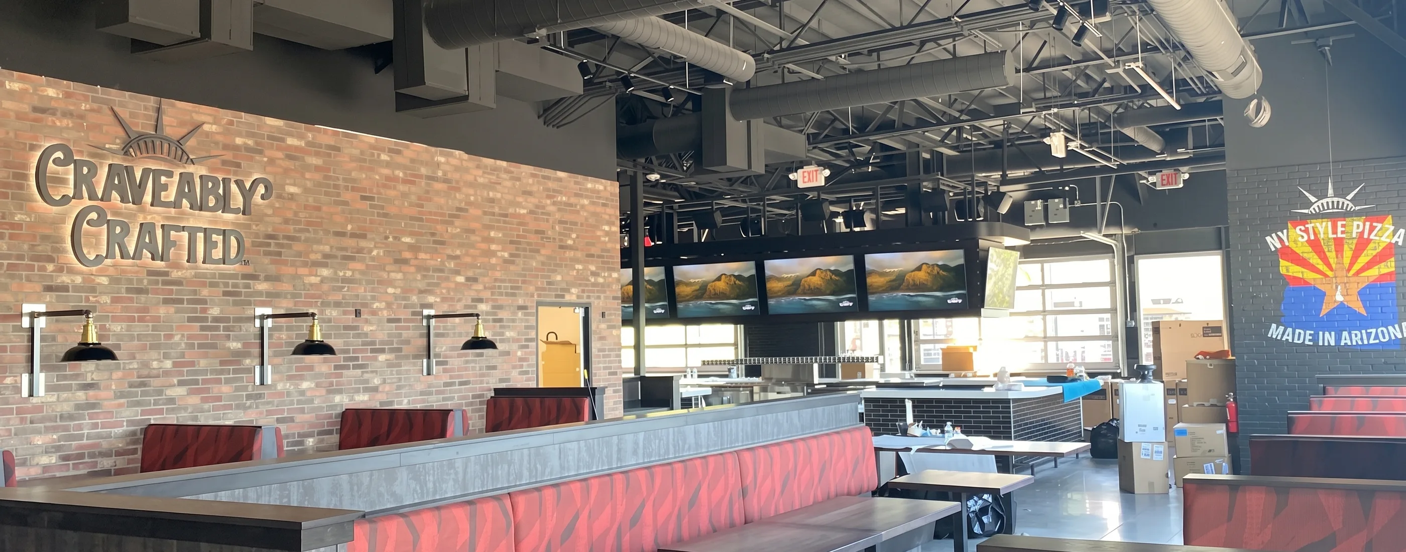 Dining room at Parry’s Pizza with brick walls, exposed ceiling, and booth seating